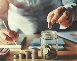 Man at his desk counting coin stacks as he moves them to a jar