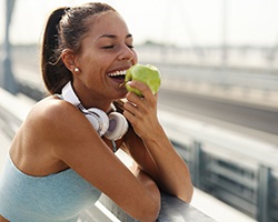 Smiling woman eating apple outside